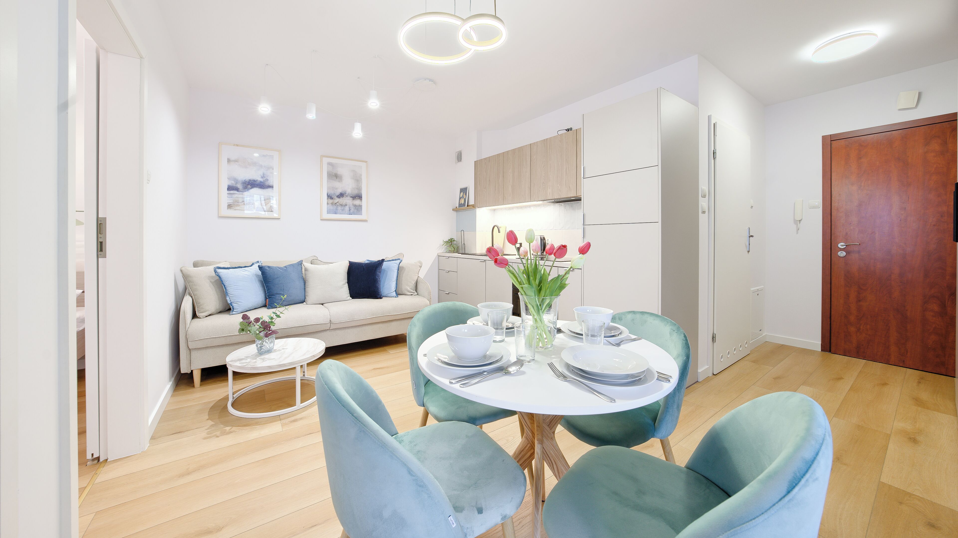 Una sala de estar moderna con un sofá, una mesa de comedor con sillas y una cocina al fondo.