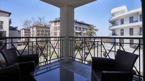 Un balcón con sillas de mimbre, vista de edificios circundantes y cielo despejado.