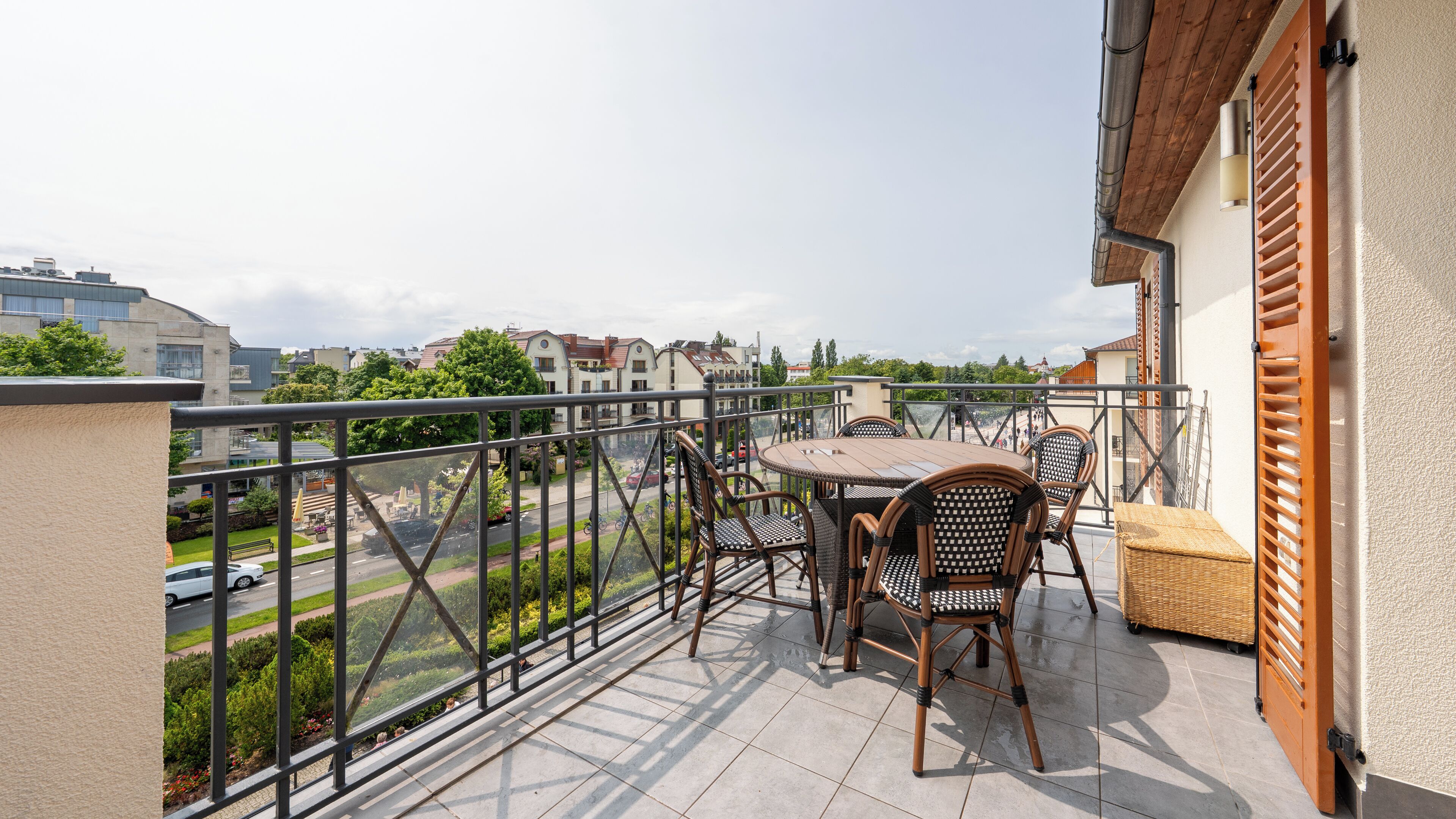 A balcony with a table and chairs, offering a view of the street and buildings.