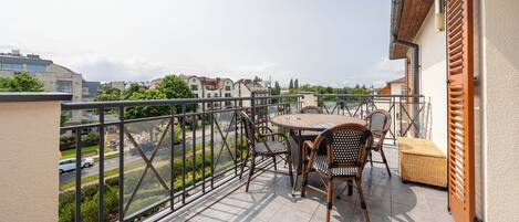 A balcony with a table and chairs, offering a view of the street and buildings.