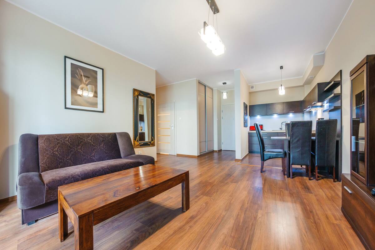 Un salon moderne comprenant un canapé, une table basse en bois et un coin repas avec des chaises et une table.
