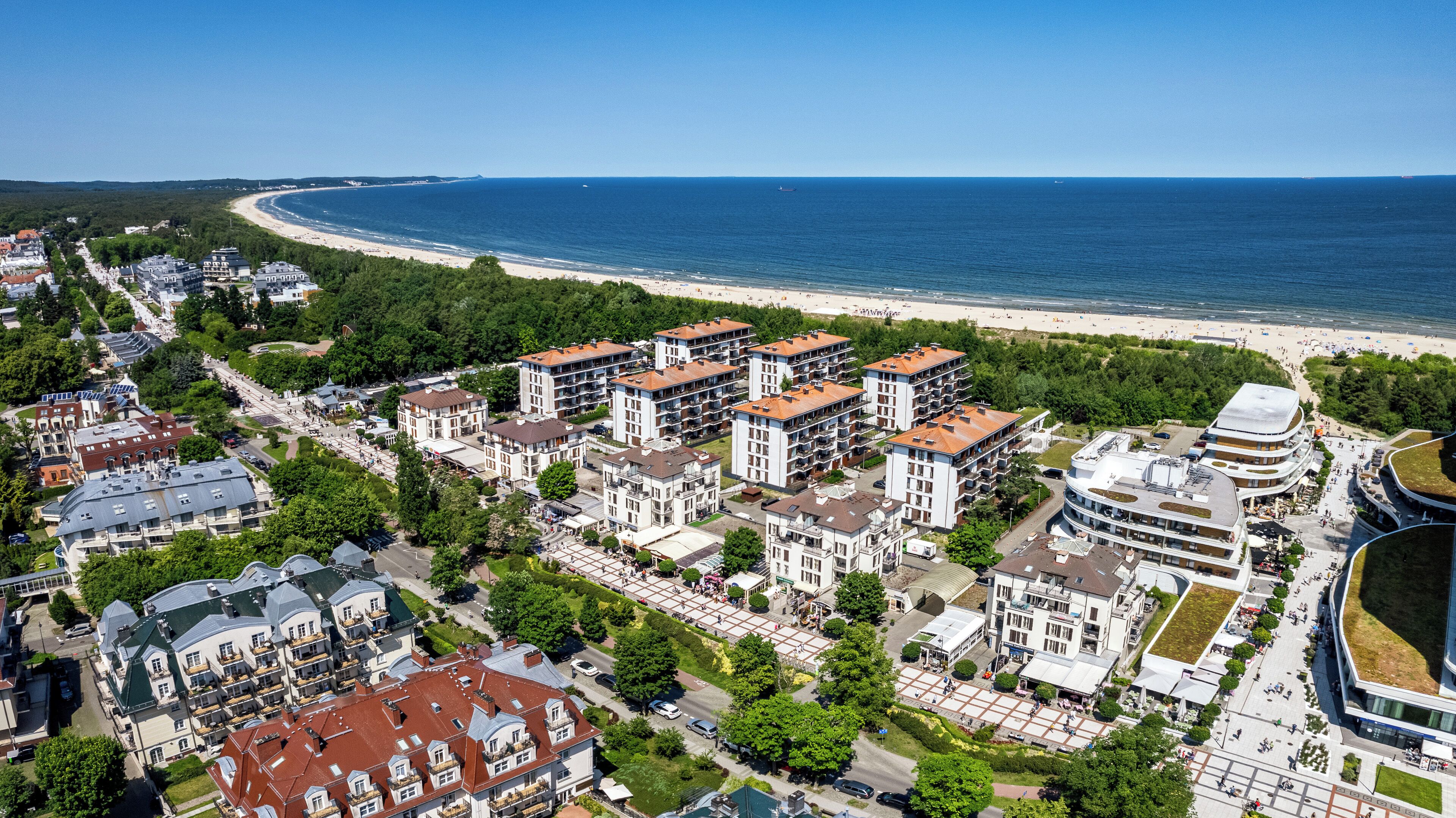 Vista aérea de una zona residencial costera con modernos edificios de apartamentos, una playa y un puerto deportivo.