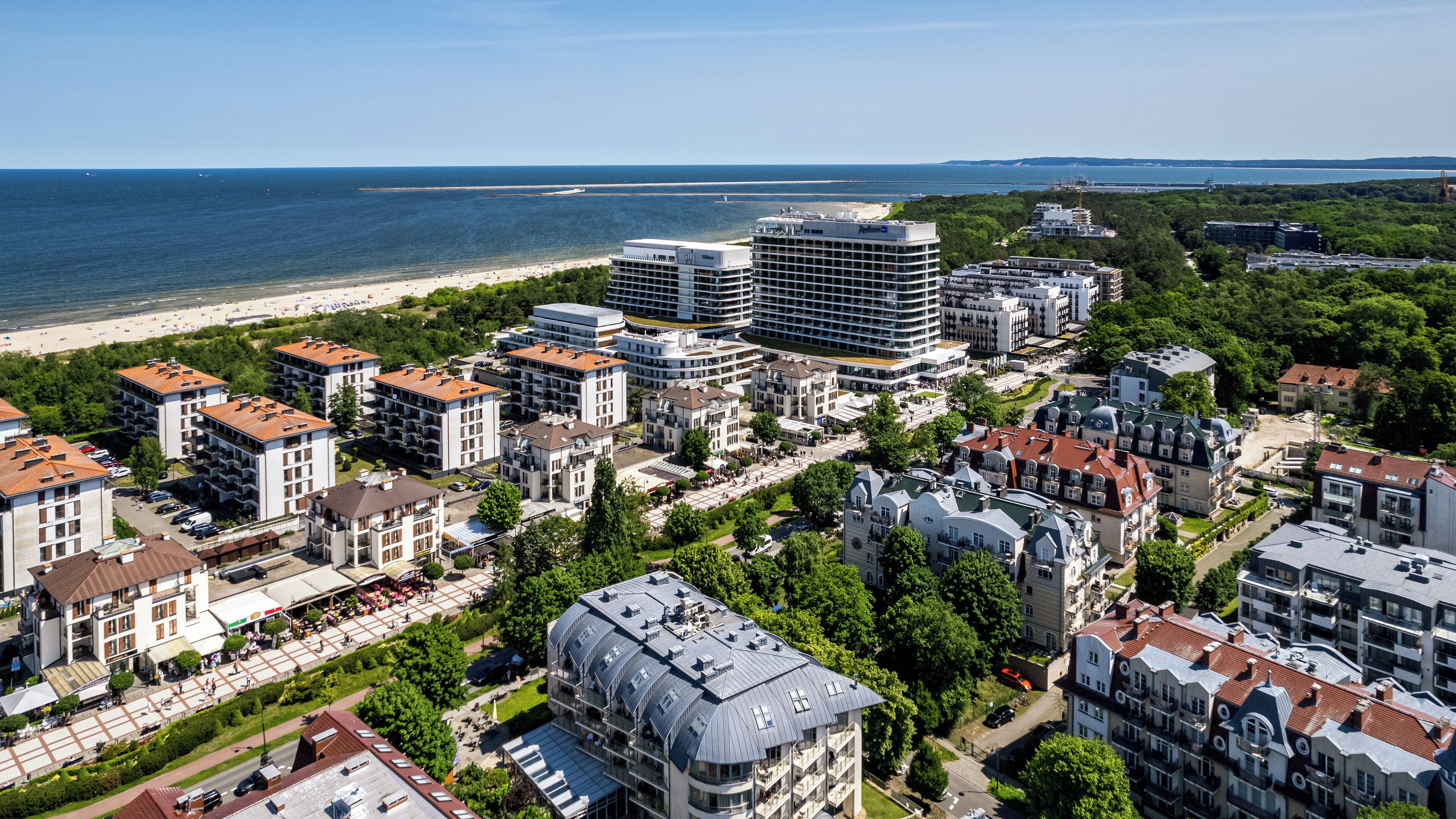 A coastal urban area with modern and traditional buildings, a beach, and a marina.