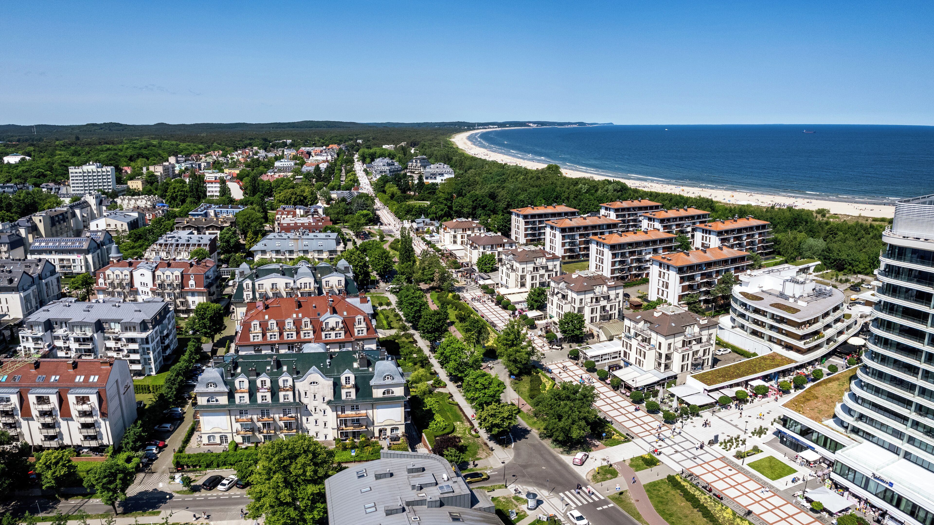 An aerial view of a coastal town with a mix of residential buildings and a modern hotel.