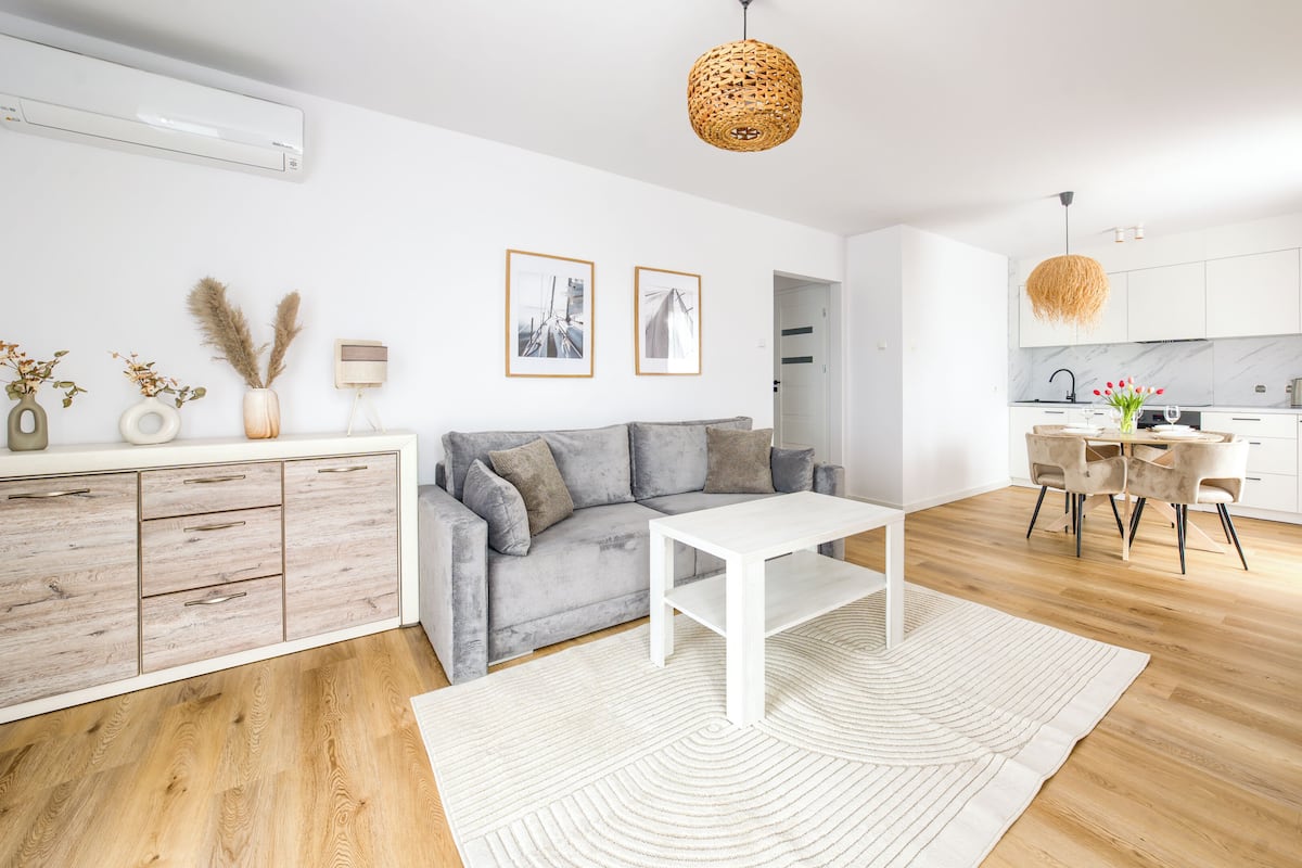 Un salon moderne avec un canapé gris, une table basse blanche et un coin repas comprenant une table et des chaises blanches.