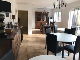 Una cocina moderna con comedor, que incluye una isla grande, armarios de madera y una lámpara de araña.