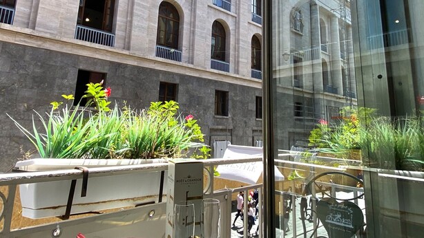 A table with snacks, a bottle, and a glass, set against a building with arched windows and balconies. - Toledo Lifestyle (Naples)
