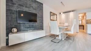 Ein moderner Essbereich mit Steinwand, Flachbildfernseher, weißen Stühlen und minimalistischem Design.