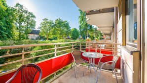 Ein Balkon mit roten Geländern, Korbstühlen und einem Tisch.