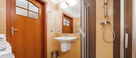 Un baño moderno con puerta de madera, lavamanos, espejo y ducha.