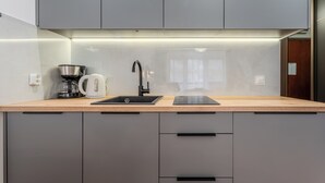 Eine moderne Küche mit integriertem Spülbecken, Wasserkocher, Kaffeemaschine und einem Tablet auf der Arbeitsfläche.