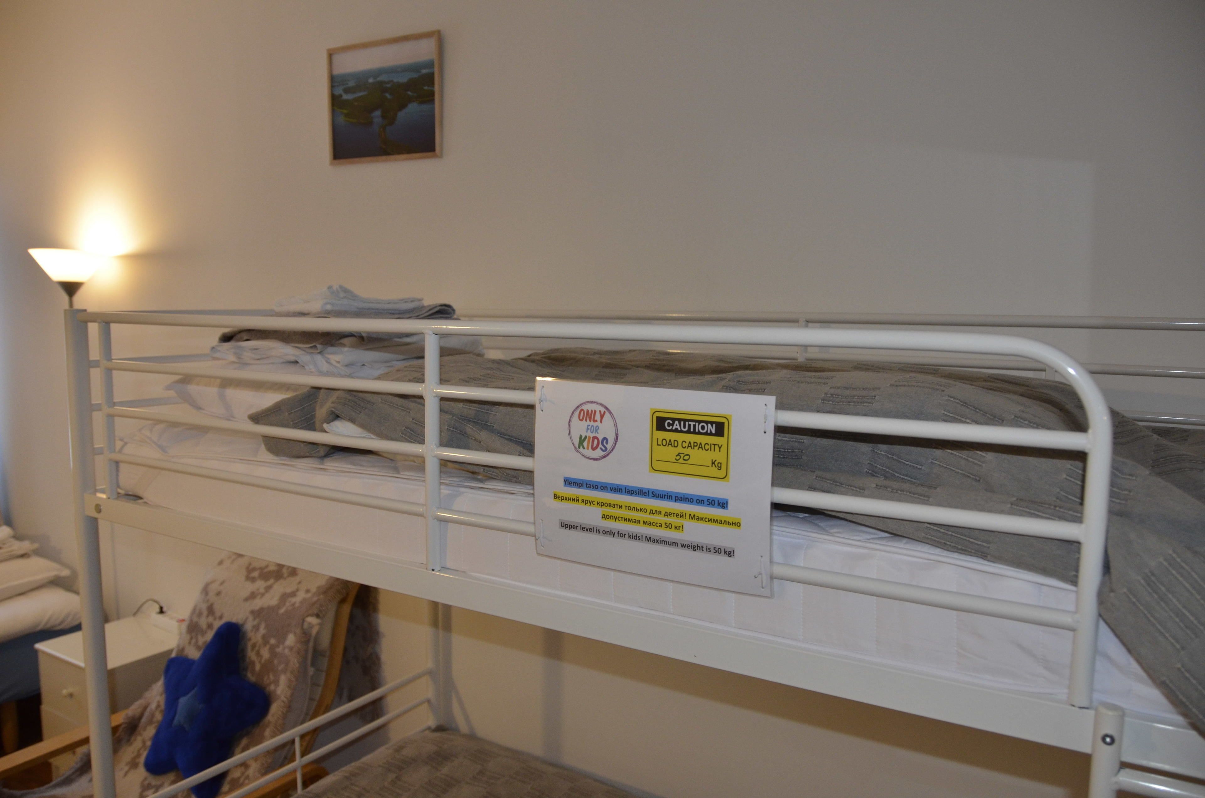 Una cama litera con una señal de precaución que indica una capacidad de carga de 50 kg.
