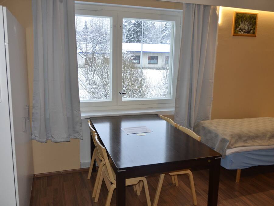 A room with a bed, a table, and a window with curtains.