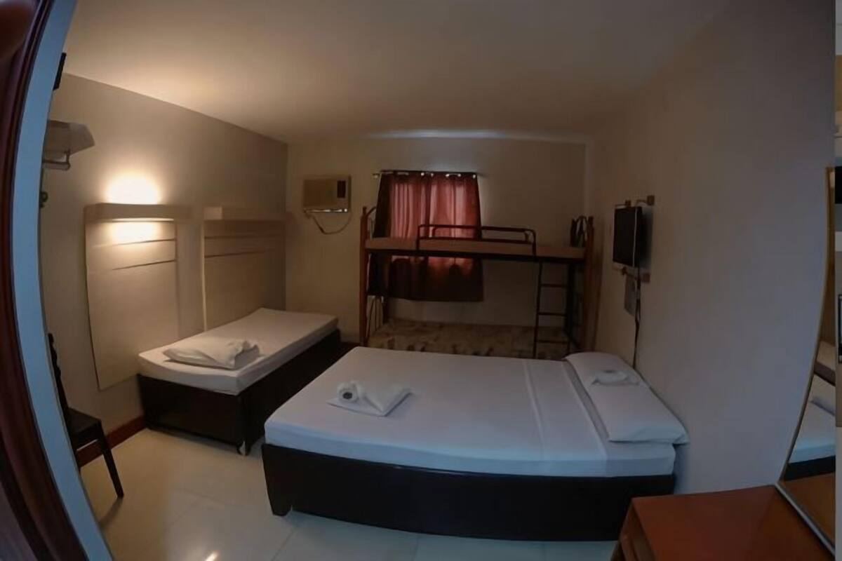 A room with bunk beds, a desk, a chair, and a bedside table.