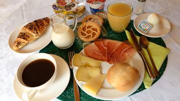 Colazione con croissant, formaggio, prosciutto, pane, caffè, succo di frutta e yogurt.