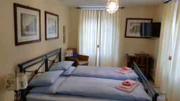 A hotel room with two beds, a desk, a chair, a television, and curtains.