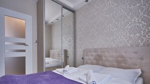 A hotel room with a bed, a purple blanket, and a mirror. - Apartamenty Sun & Snow Platan (Swinoujscie)