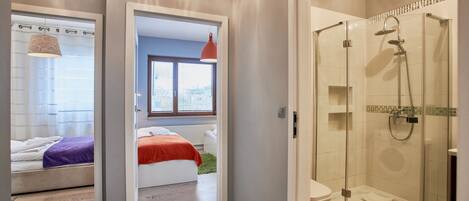 A modern bathroom with a glass-enclosed shower, a white toilet, and a visible window.