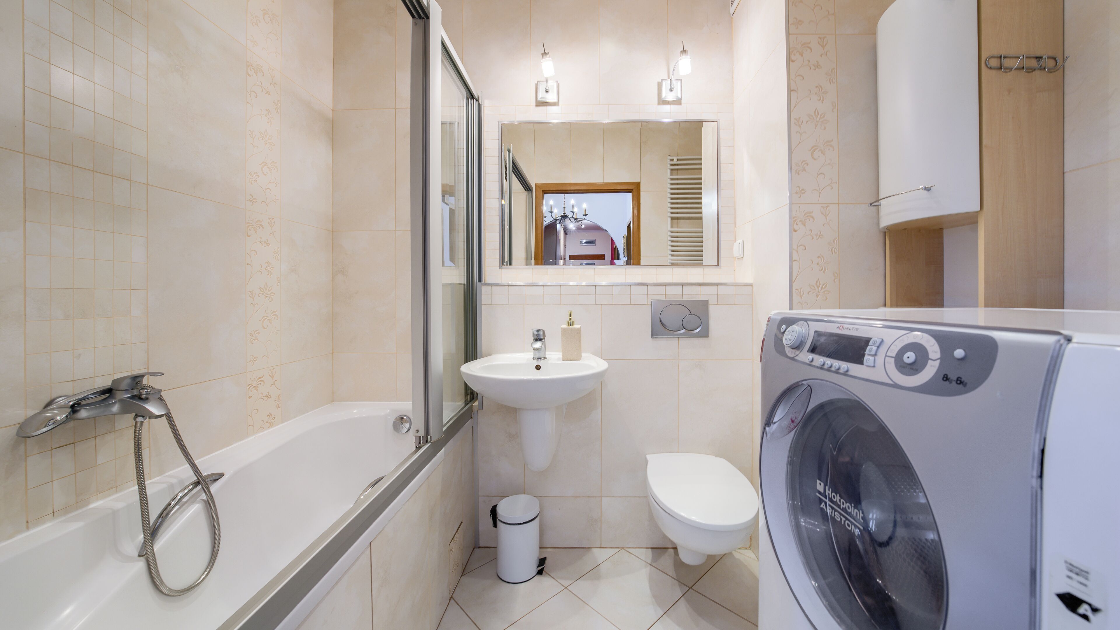 A bathroom with a bathtub, sink, toilet, and a front-loading washing machine.