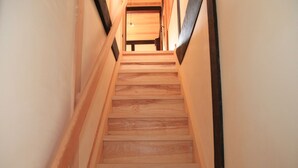 A wooden staircase with a handrail on both sides, leading to a room with a wooden door at the top. - Temari Hotel Yukikai (Kurashiki)