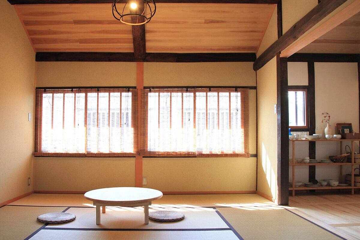 Una habitació japonesa tradicional amb tatamis, una taula baixa i una finestra amb persianes menjades.