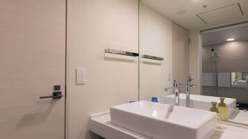 A modern bathroom with a white sink, a mirror, and a shower.