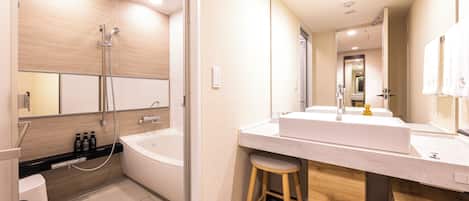 A modern bathroom with a bathtub, a large mirror, a vanity with a sink, and a stool.