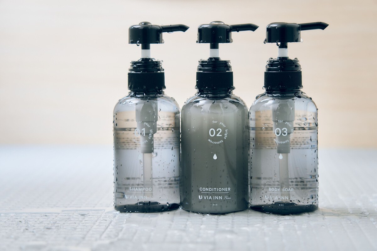 Three transparent bottles labeled 01, 02, and 03 with pumps, containing shampoo, conditioner, and body soap, respectively.