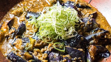 A dish with eggplant and meat in a brown bowl.