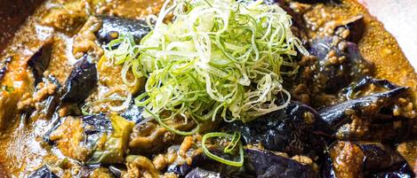 A dish with eggplant and meat in a brown bowl.