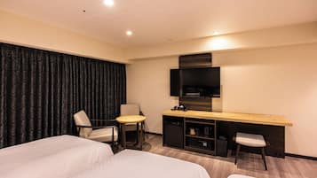 A hotel room with two beds, a desk with a TV, and a small kitchenette.