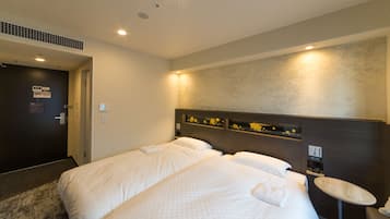 Habitación de hotel con dos camas, una mesita redonda y un estante en la pared decorado con objetos.