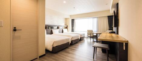 A hotel room with two beds, a desk, a chair, and a television.