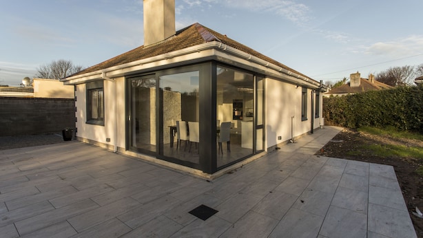 A modern house with a glass extension, a tiled patio, and a chimney. - Killester Self Catering Cottage (Dublin)
