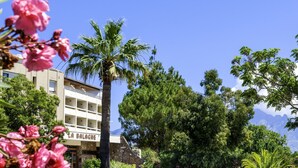 A hotel with a balcony, surrounded by lush greenery and a clear blue sky. - Village Club Miléade Calvi (Calvi)