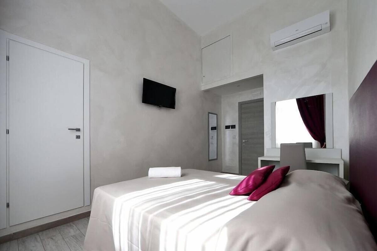 A hotel room with a bed, a television, a wardrobe, and a mirror.