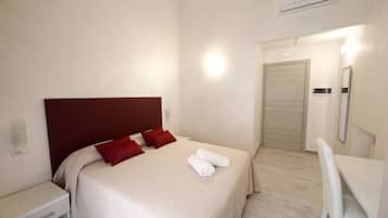 Une chambre d’hôtel avec un lit, un bureau, une chaise et une porte.
