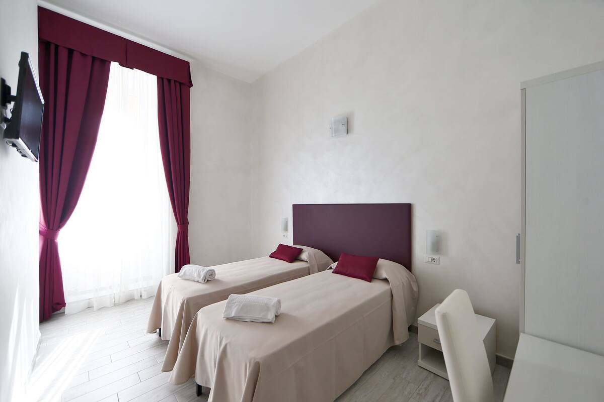 A hotel room with two beds, each with a headboard, and a white chair.
