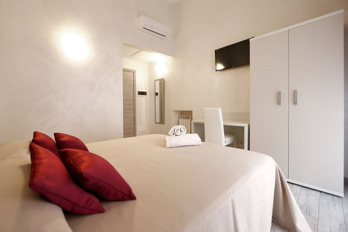 A hotel room with a bed, a wardrobe, a mirror, and a towel.