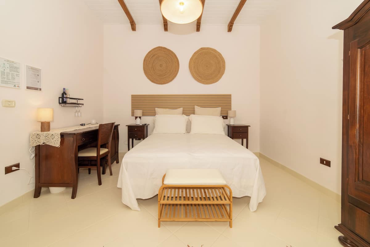A bedroom with a wooden bed, bedside tables, a desk, and a chair. There are two wall-mounted circular decorations above the bed.
