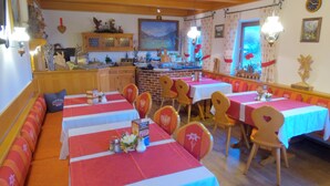 Un restaurante con varias mesas cubiertas con manteles rojos y blancos, sillas de madera y una pared de ladrillo al fondo.