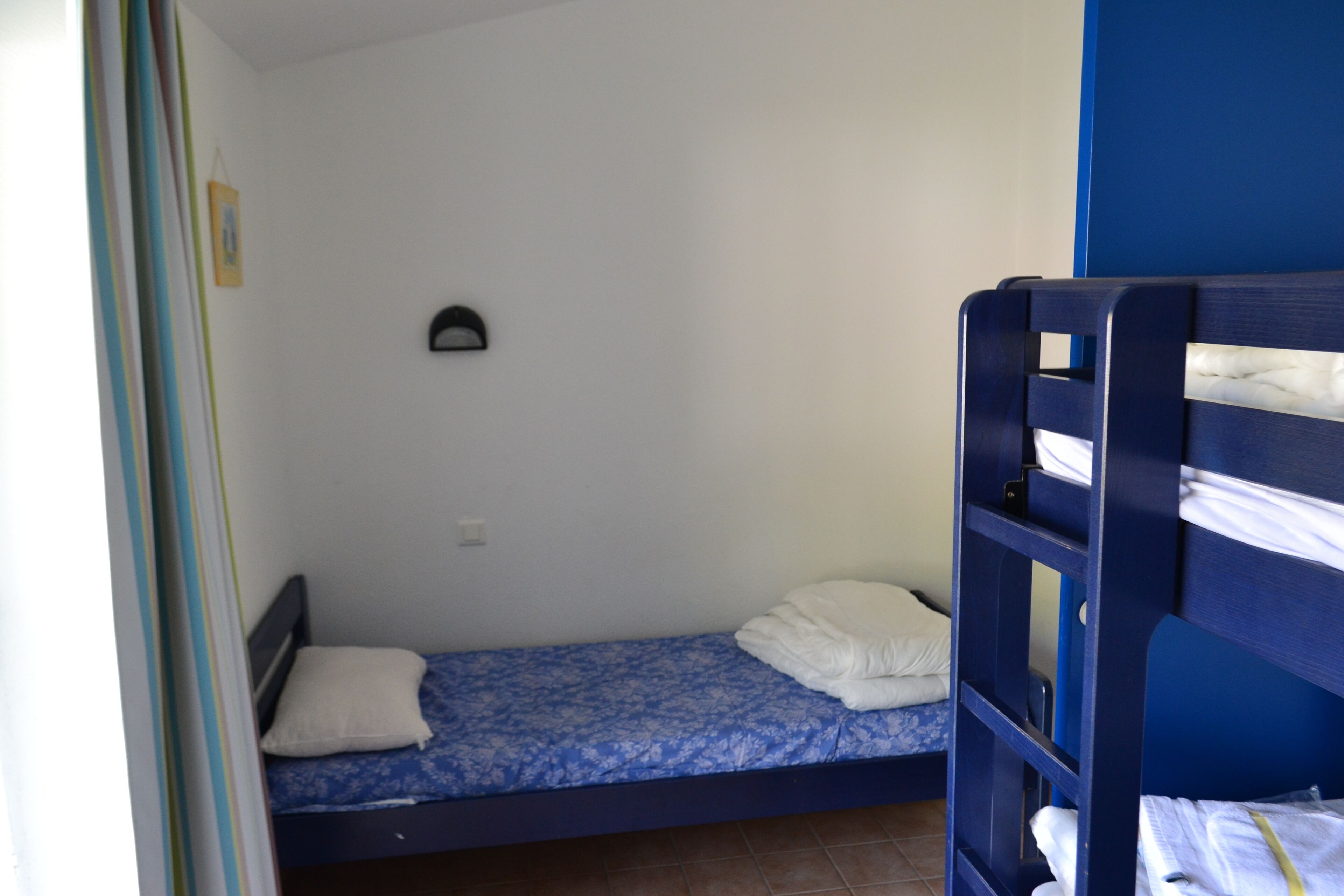 A small, single-bed room with a bunk bed on one side.