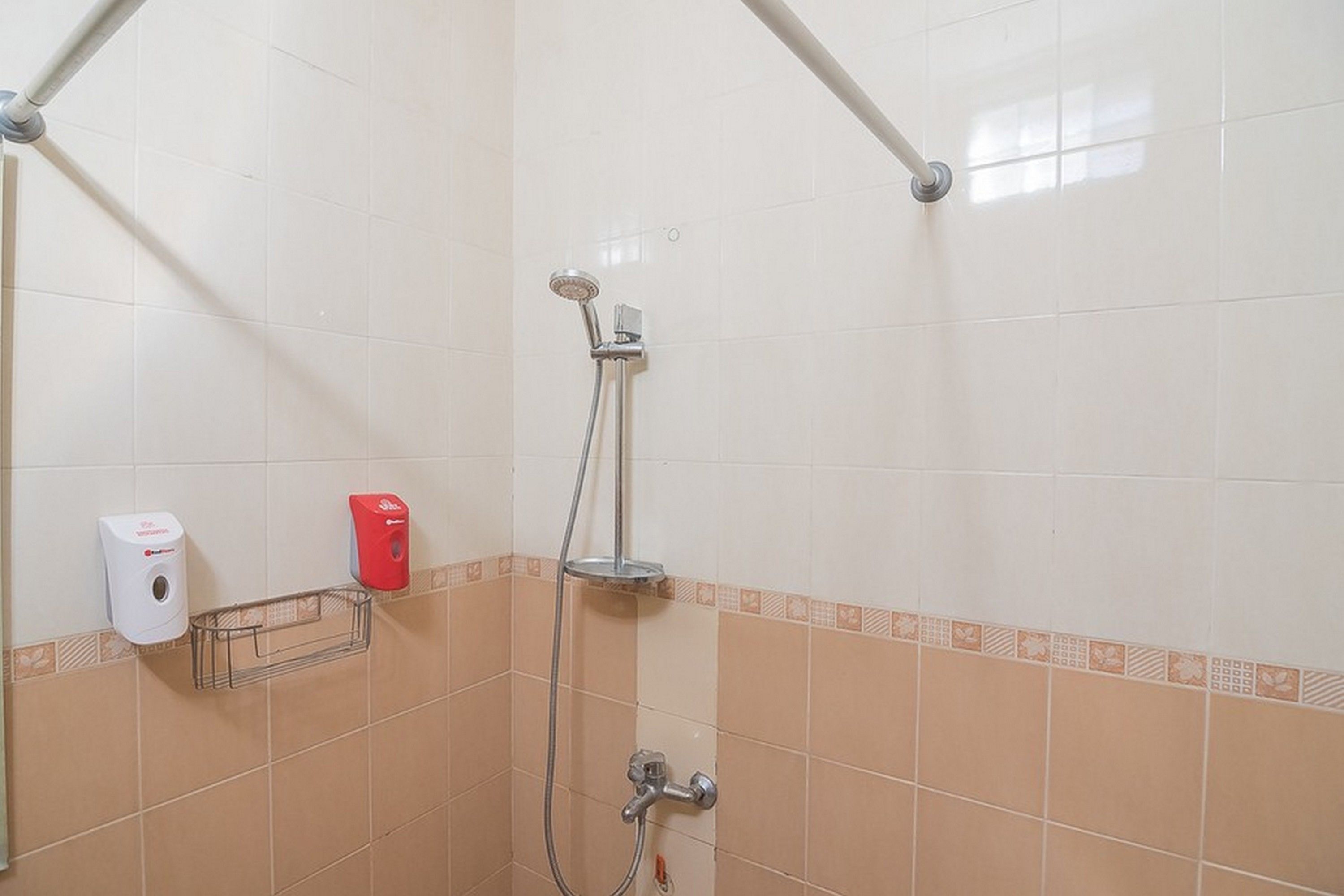 A shower area with a handheld showerhead, a wall-mounted soap dispenser, and a towel rack.
