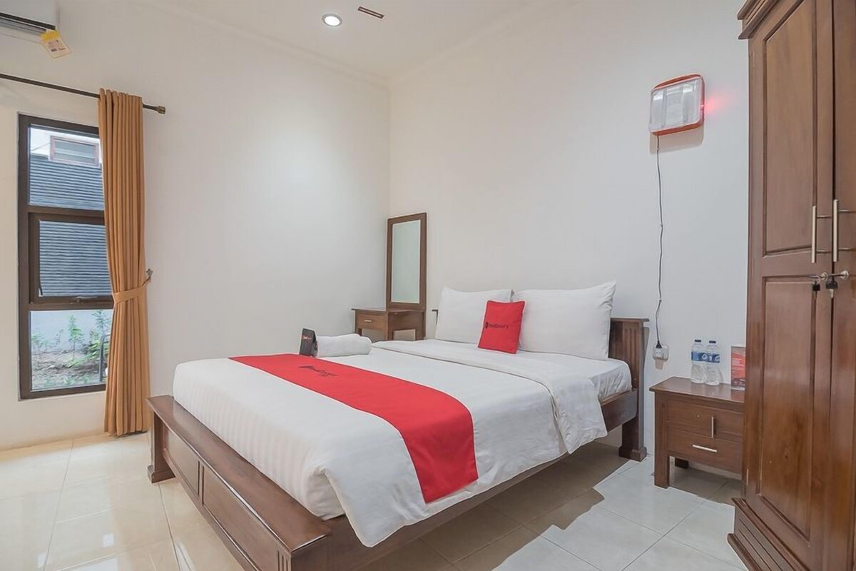 Una habitación de hotel con una cama grande, una mesita de noche, un armario y una ventana con cortinas.