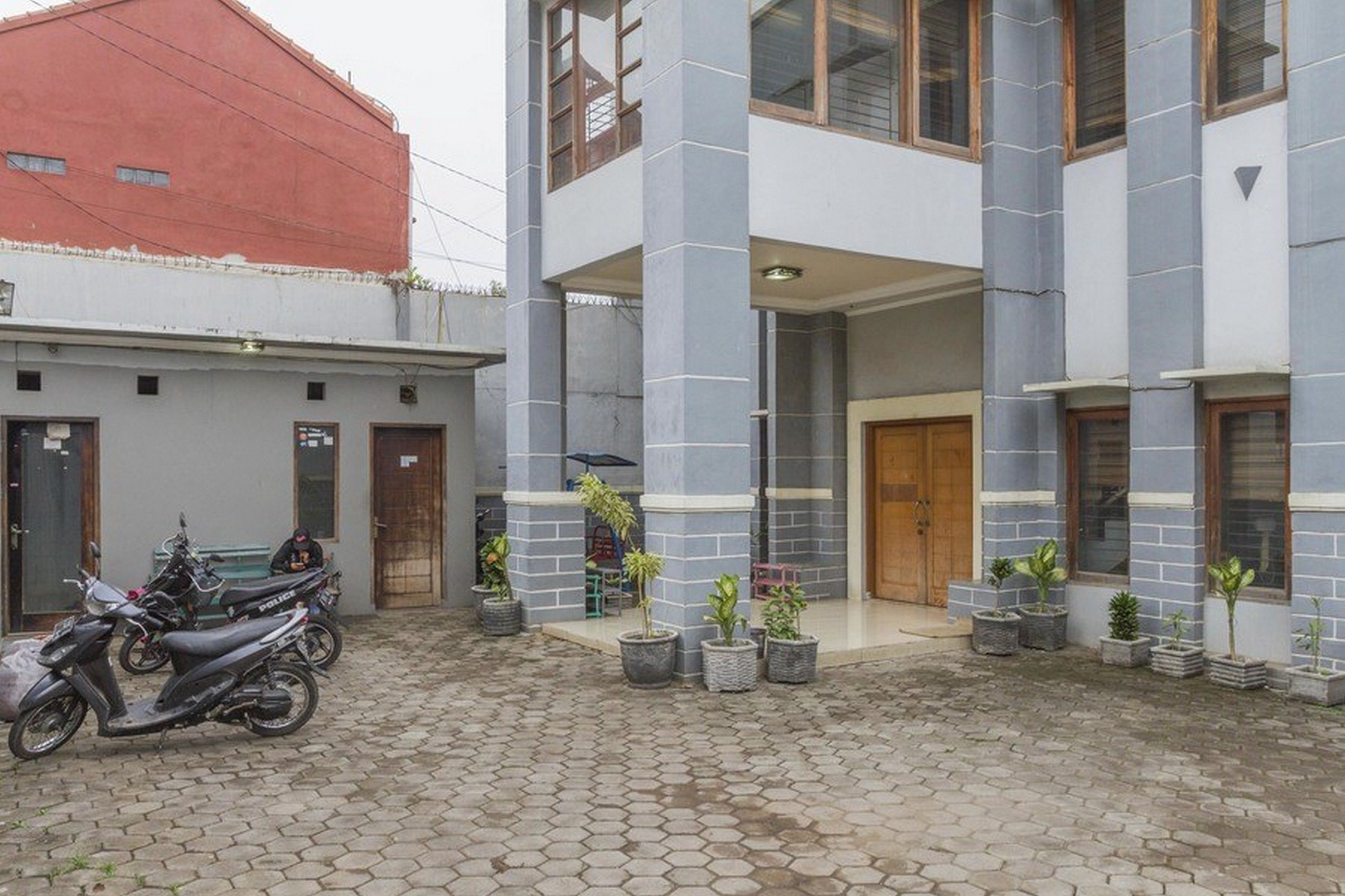 Edifici amb pati, plantes en testos i una moto.