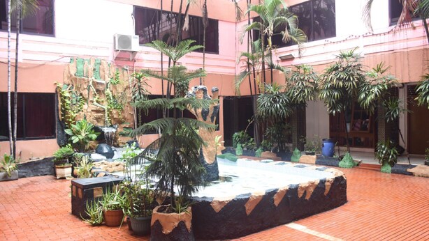 Un patio con plantas en macetas, fuente de agua y suelo de ladrillo.