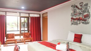 Habitación de hotel con una cama grande, cortinas rojas, un adorno de pared rojo y blanco, y una ventana con persianas.