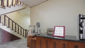 Un comptoir d’accueil avec une pancarte encadrée, un escalier et un distributeur d’eau.