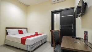 Une chambre d’hôtel avec un lit, un bureau, une chaise, une télévision et une porte.