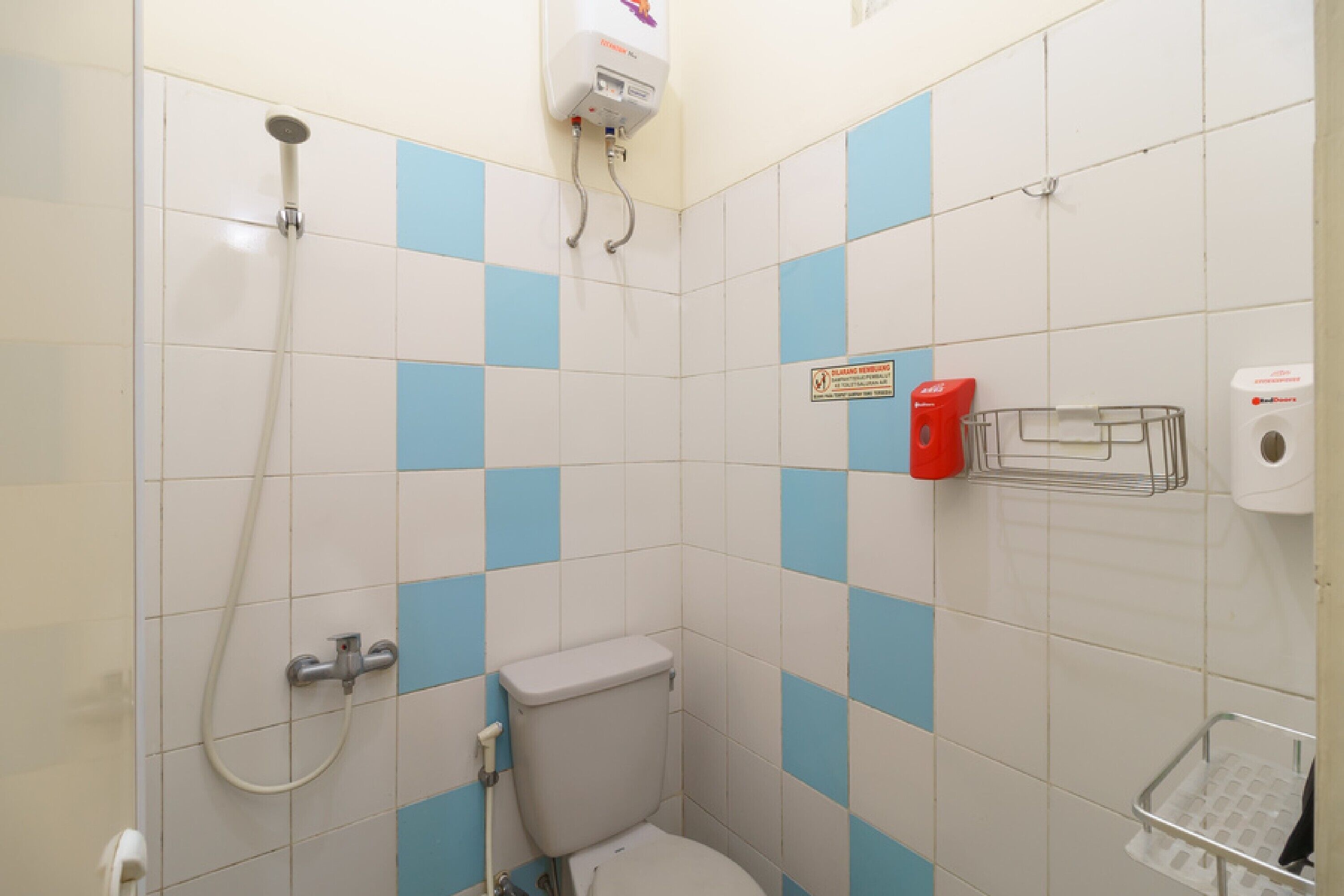 A small bathroom with a toilet, a shower, and a hand dryer.